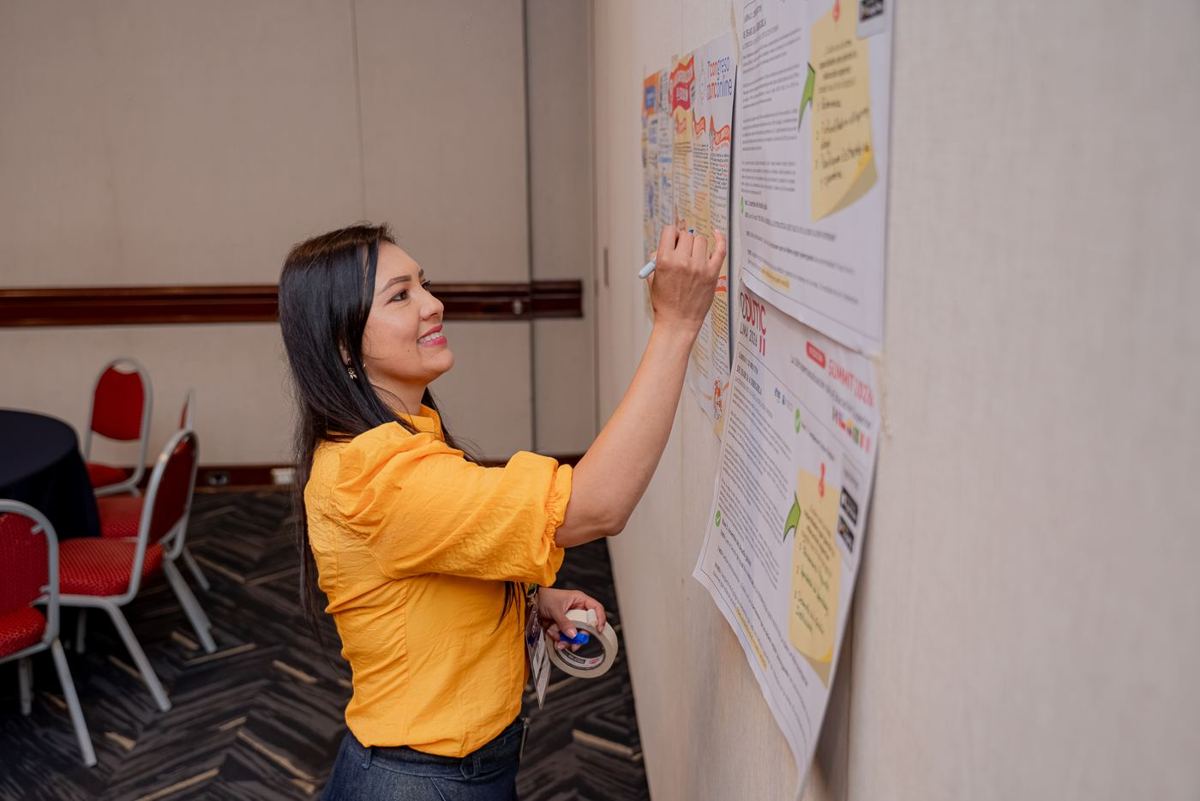 Participante escribe en el muro de trabajo del Summit