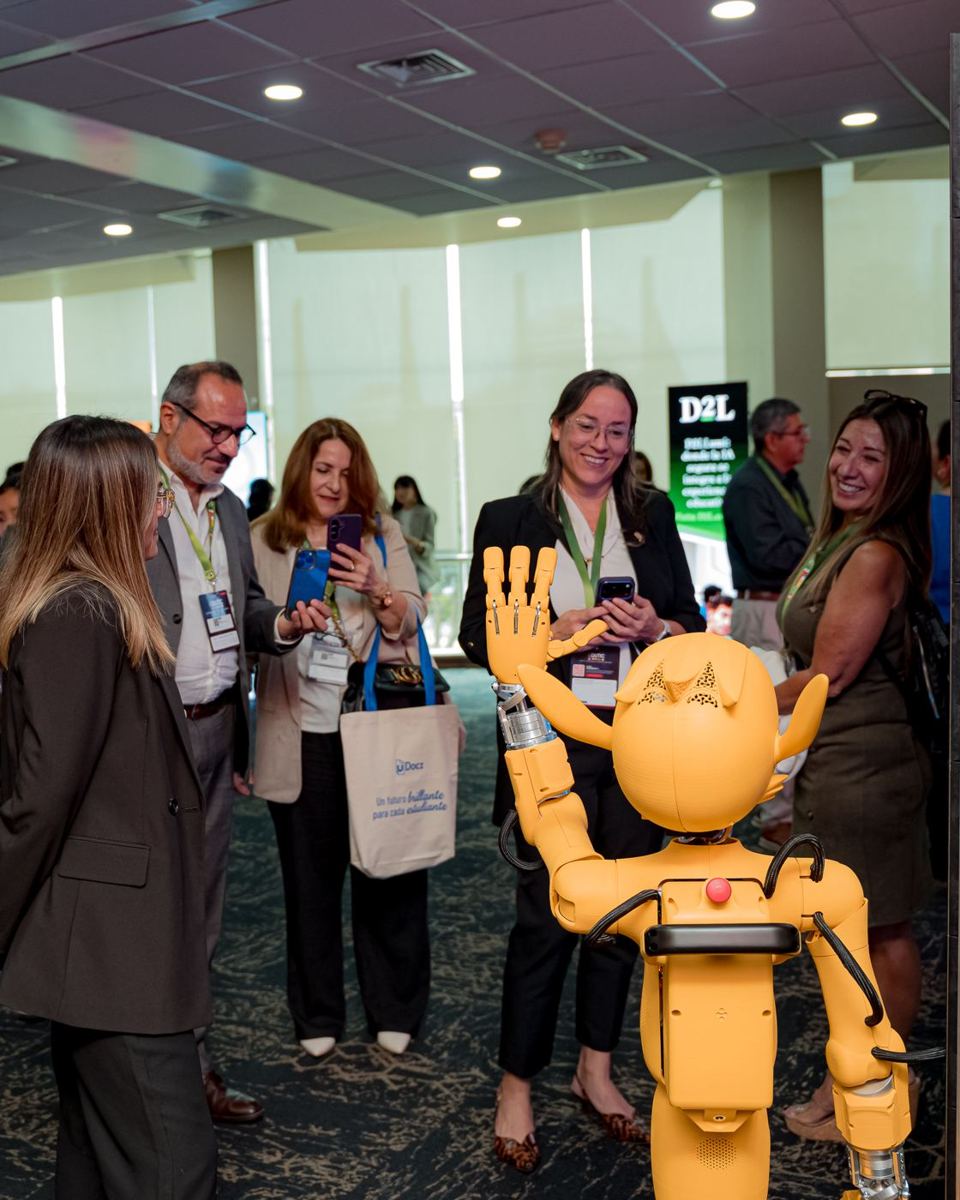 Asistentes saludan a un robot en la zona de exhibición